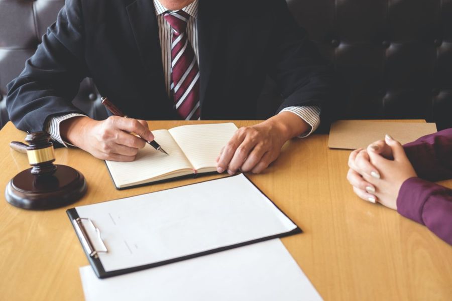 Dos personas reunidas en oficina, una de ellas escribiendo en una agenda, representando la gestión experta y control riguroso en procesos de ejecución